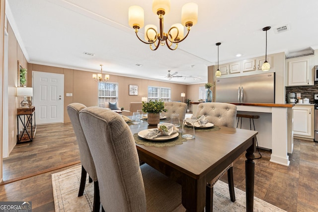 dining room featuring dark wood finished floors, visible vents, ceiling fan with notable chandelier, and crown molding