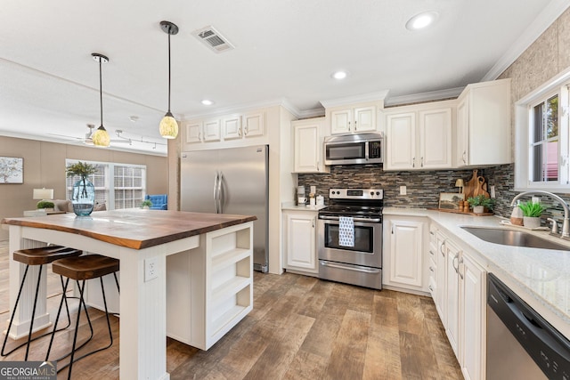 kitchen featuring visible vents, backsplash, butcher block counters, stainless steel appliances, and a sink