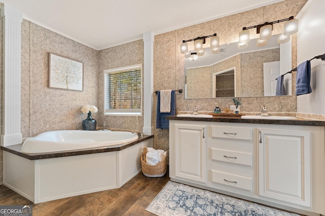 full bath featuring a sink, wood finished floors, double vanity, and a bath