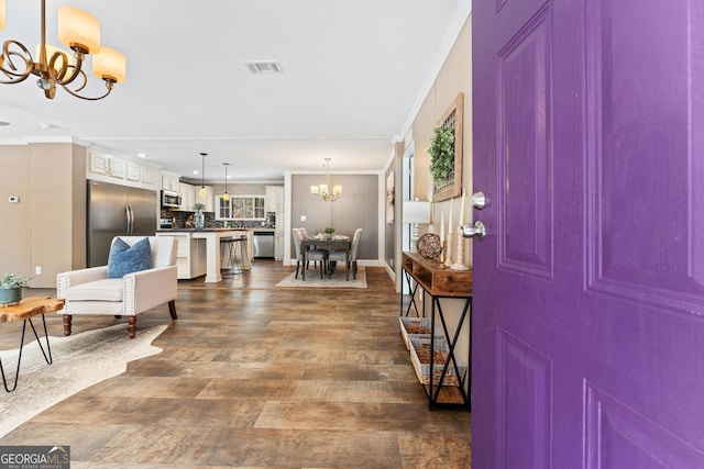 foyer featuring a notable chandelier, baseboards, visible vents, and ornamental molding