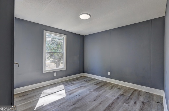 empty room featuring wood finished floors, baseboards, and a textured ceiling