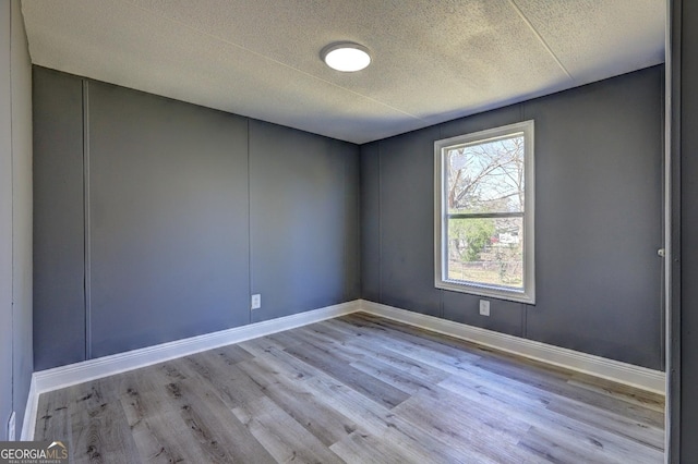 unfurnished room featuring baseboards, a textured ceiling, and wood finished floors