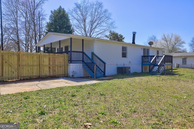 back of property featuring stairway, a lawn, central AC unit, and fence