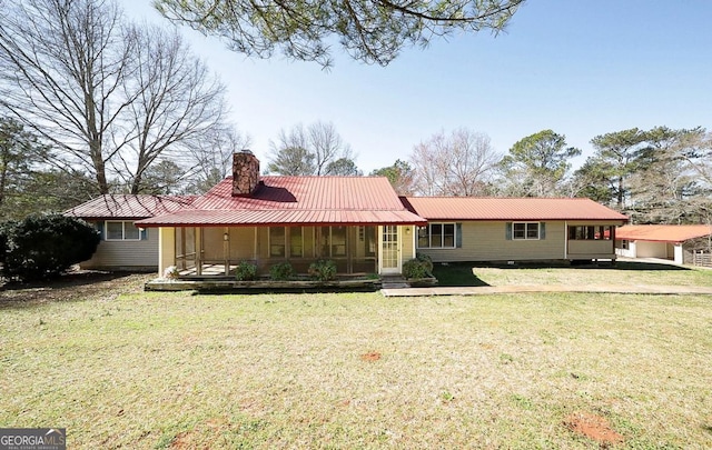 back of property featuring a lawn, a chimney, and metal roof