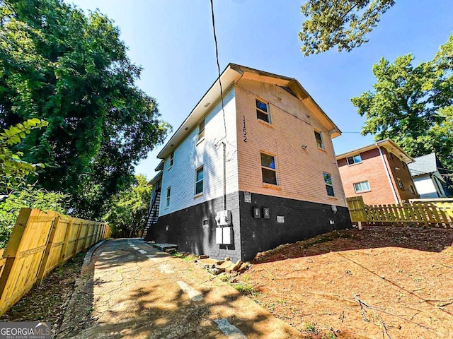 view of side of home featuring brick siding and fence