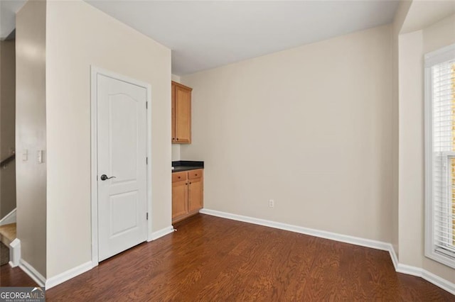 empty room featuring dark wood finished floors, stairway, and baseboards