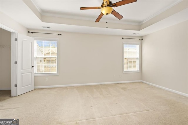 spare room with a tray ceiling, carpet, and visible vents