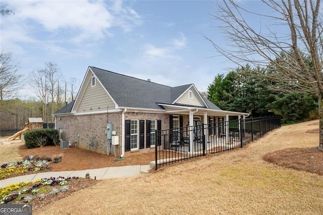 view of front of house with brick siding, a playground, fence, central air condition unit, and a patio area