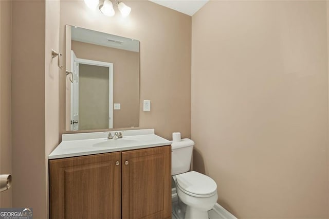 half bath with vanity, toilet, and visible vents