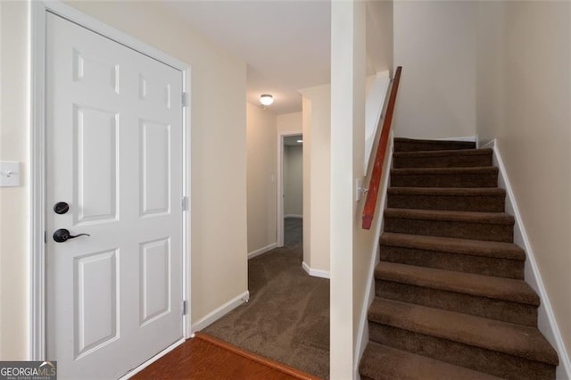 stairway featuring baseboards and carpet