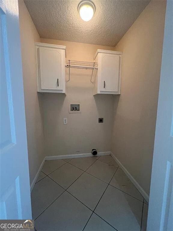 clothes washing area featuring electric dryer hookup, a textured ceiling, light tile patterned floors, baseboards, and hookup for a washing machine