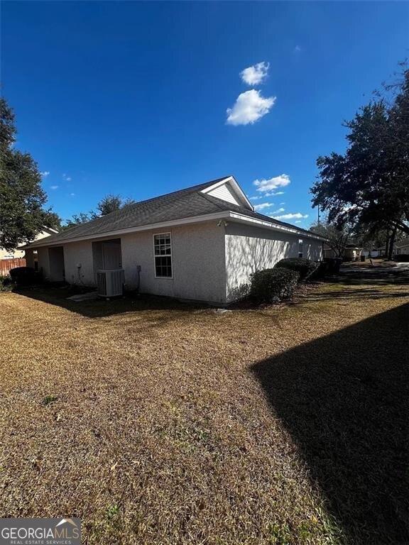 rear view of house with stucco siding and central AC