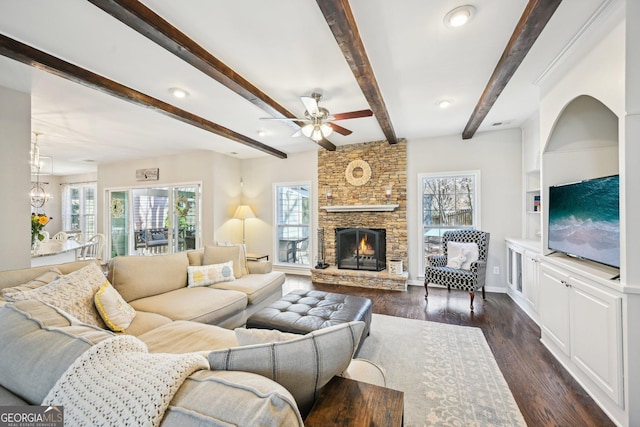 living room with a fireplace, beamed ceiling, ceiling fan with notable chandelier, and dark wood-style flooring