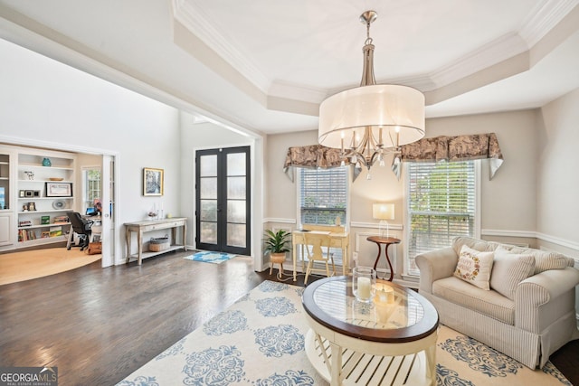 living room with a notable chandelier, wood finished floors, french doors, crown molding, and a raised ceiling