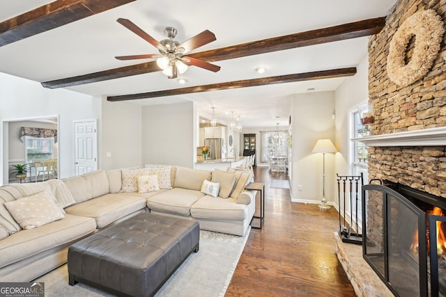 living area featuring baseboards, plenty of natural light, wood finished floors, and ceiling fan with notable chandelier