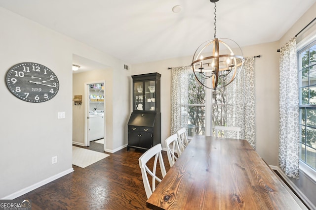 unfurnished dining area featuring visible vents, wood finished floors, baseboards, washer / dryer, and a chandelier