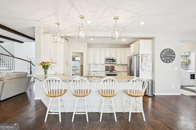 kitchen featuring light stone countertops, a peninsula, washer / clothes dryer, a sink, and appliances with stainless steel finishes