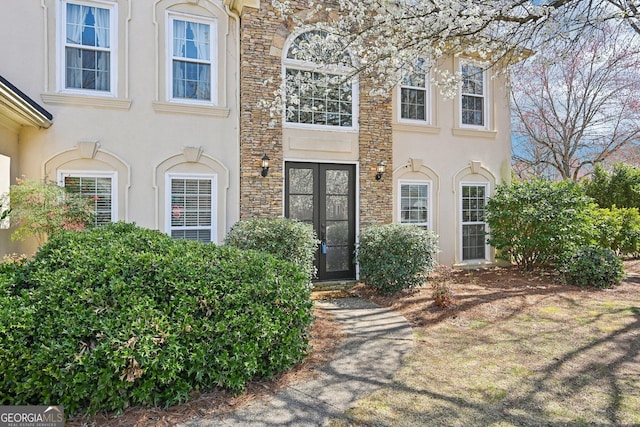 view of exterior entry with stucco siding and stone siding