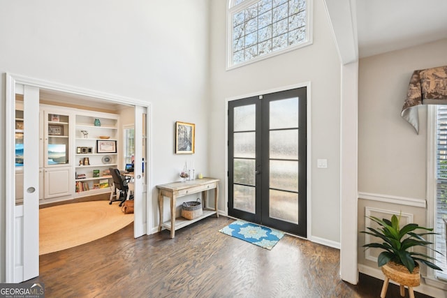 foyer entrance with dark wood finished floors, french doors, and a high ceiling