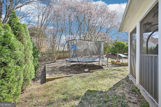 view of yard with a trampoline and fence