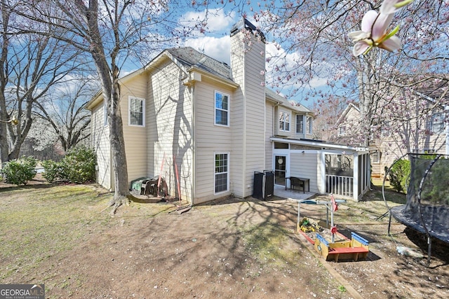 back of property featuring a trampoline, a patio area, and a chimney