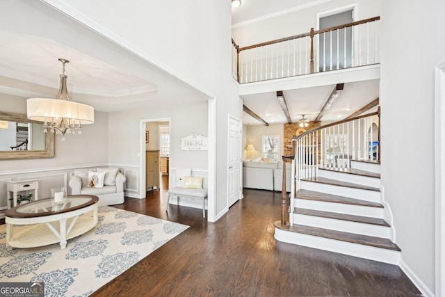 living room featuring stairway, wood finished floors, crown molding, and a chandelier