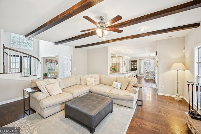 living room featuring baseboards, beam ceiling, dark wood finished floors, and ceiling fan with notable chandelier