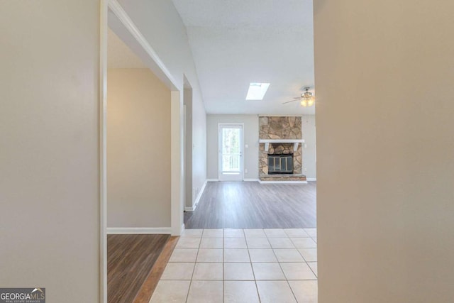 hall featuring a skylight, baseboards, and wood finished floors