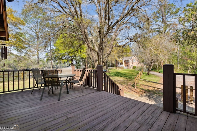 wooden deck with outdoor dining area and a yard