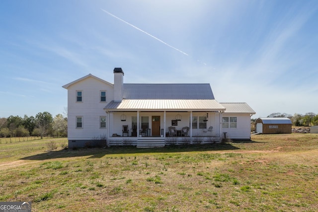 back of house with covered porch, an outdoor structure, crawl space, a lawn, and metal roof