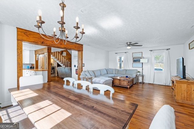 living room featuring stairway, ceiling fan with notable chandelier, a textured ceiling, and wood finished floors