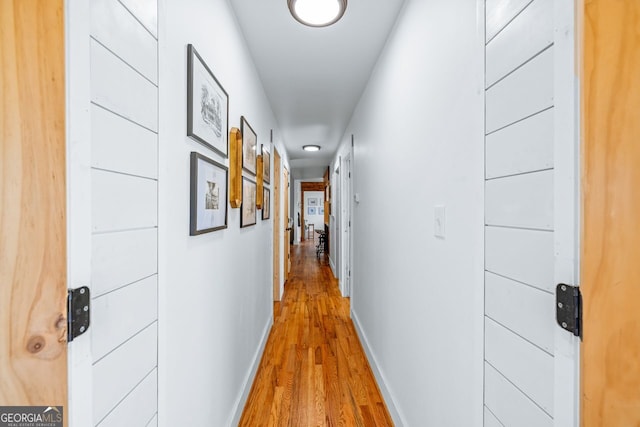 corridor featuring light wood-type flooring and baseboards