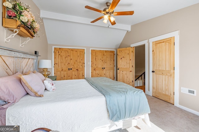 carpeted bedroom with visible vents, multiple closets, a ceiling fan, lofted ceiling with beams, and baseboards