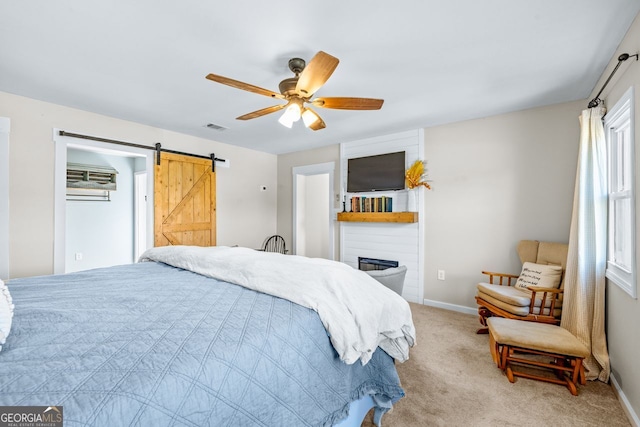 bedroom with visible vents, baseboards, ceiling fan, a barn door, and light colored carpet