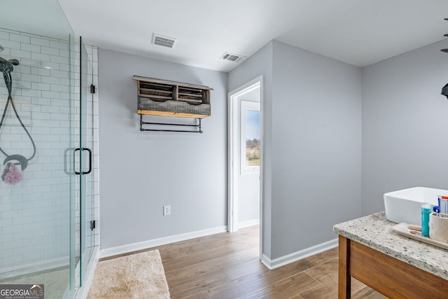 full bathroom featuring baseboards, wood finished floors, visible vents, and a stall shower