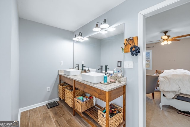 bathroom with double vanity, wood finished floors, baseboards, and a sink