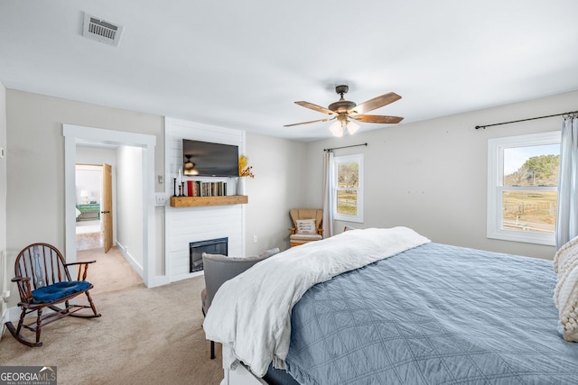 bedroom with visible vents, a large fireplace, baseboards, light colored carpet, and ceiling fan