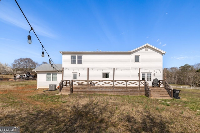 rear view of property with central air condition unit, a lawn, metal roof, and a wooden deck