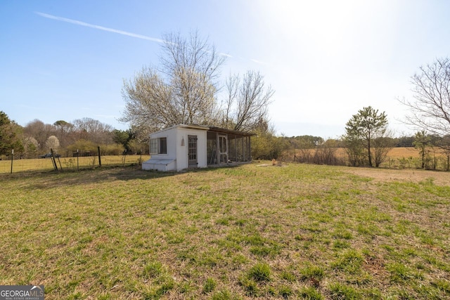 view of yard featuring an outbuilding, a rural view, and fence