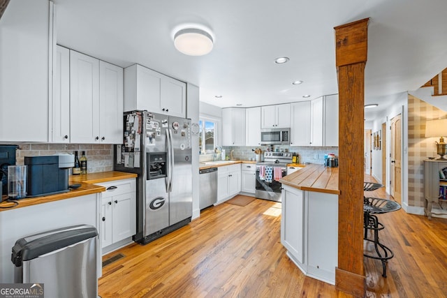 kitchen with a breakfast bar, white cabinets, stainless steel appliances, and a sink