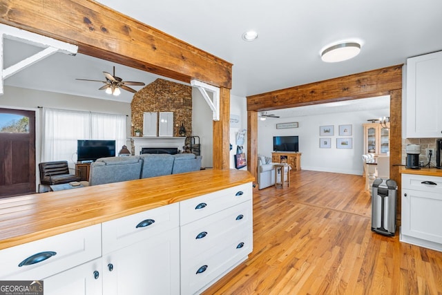 kitchen with light wood-type flooring, wooden counters, open floor plan, and a fireplace