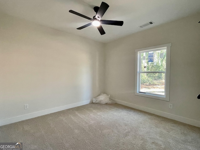 carpeted spare room with visible vents, ceiling fan, and baseboards