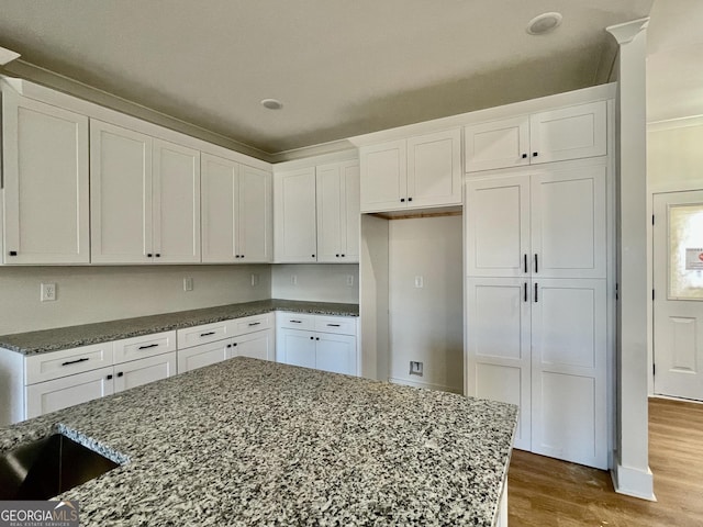 kitchen featuring dark stone counters, white cabinets, and wood finished floors