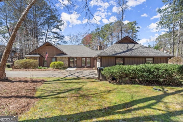 view of front of property featuring a front lawn, a garage, driveway, and a shingled roof