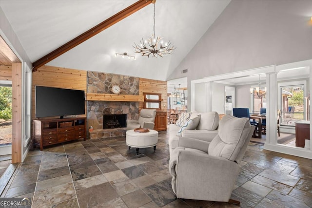 living room featuring beamed ceiling, a notable chandelier, stone tile floors, and a healthy amount of sunlight