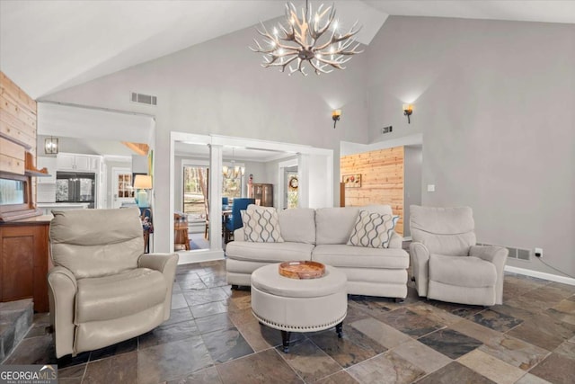 living area featuring an inviting chandelier, stone tile floors, baseboards, and visible vents