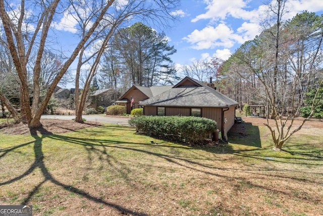 view of property exterior with a lawn and a shingled roof