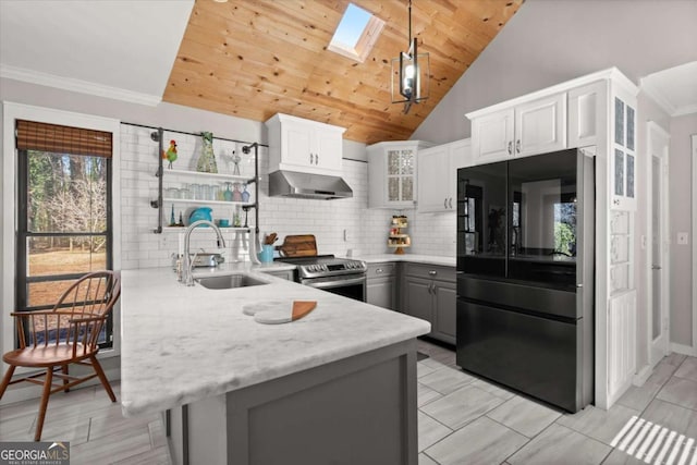 kitchen with extractor fan, refrigerator with glass door, stainless steel range with electric cooktop, a skylight, and a sink