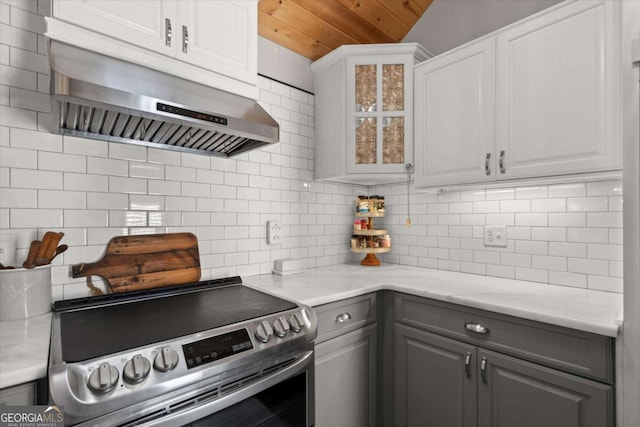 kitchen with electric range, gray cabinets, decorative backsplash, glass insert cabinets, and under cabinet range hood