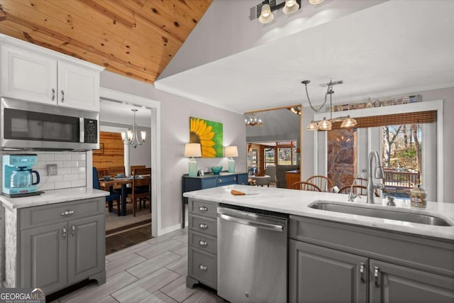 kitchen featuring a sink, appliances with stainless steel finishes, gray cabinets, and an inviting chandelier